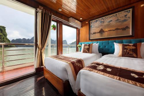 2 camas en una habitación con ventana grande en Cozy Bay Classic Cruise, en Ha Long