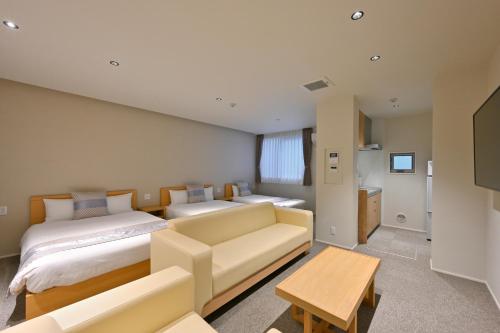 a living room with two beds and a couch at GRAND BASE Hiroshima Peace Memorial Park in Hiroshima