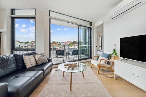 a living room with a couch and a tv at Light Filled 2BR Apt with Balcony, Parking, Cafes & Restaurants in Melbourne