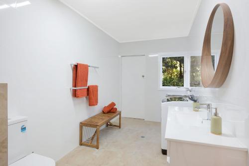 ein weißes Badezimmer mit einem Waschbecken und einem Spiegel in der Unterkunft Aque Blu - 11 Hillcrest Ave North Narooma in Kianga