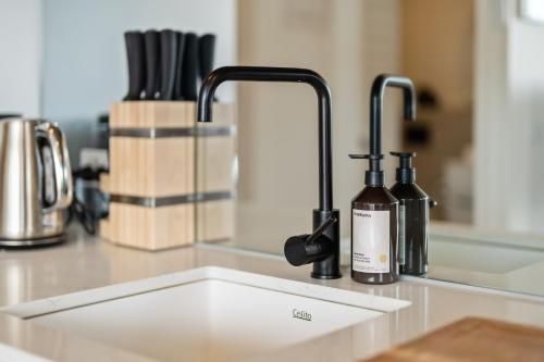 a kitchen counter with a sink and two faucets at Light Filled 2BR Apt with Balcony, Parking, Cafes & Restaurants in Melbourne