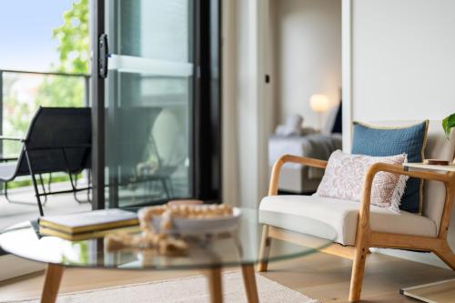 a living room with a glass coffee table and a chair at Light Filled 2BR Apt with Balcony, Parking, Cafes & Restaurants in Melbourne