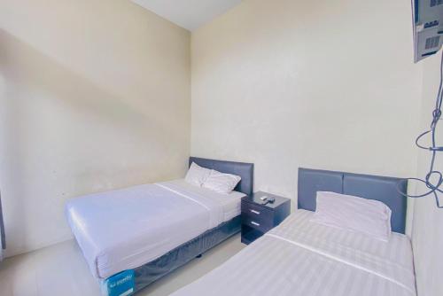 Duas camas num pequeno quarto com paredes brancas em RedDoorz Syariah near Universitas Muhammadiyah Jember em Jember