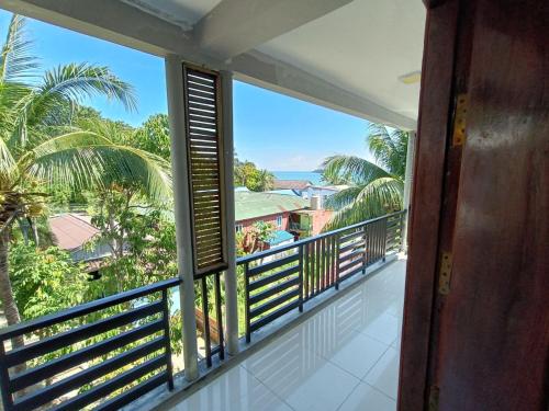 a balcony with a view of the ocean and palm trees at Roomy Guesthouse in Koh Rong Island