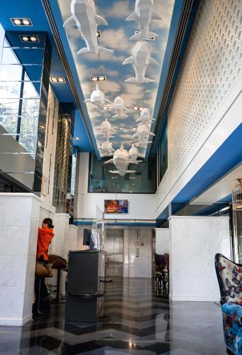 a person sitting at a table in a lobby with a ceiling at Hotel Clover Asoke - SHA Extra Plus in Bangkok