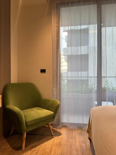 a green chair in a bedroom with a window at La Green Hotel and Residence in Bang Tao Beach