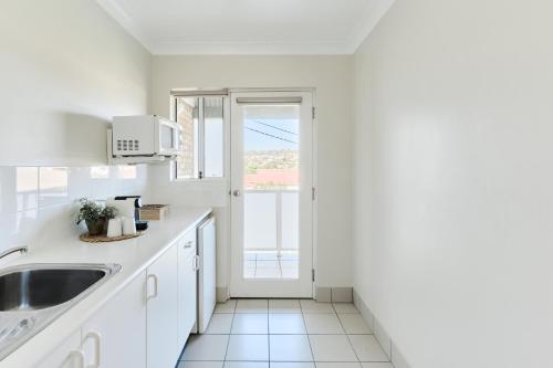 una cucina bianca con lavandino e finestra di Harbourview House a Bermagui