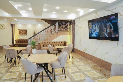 ビシュケクにあるRivieraのテーブルと椅子、壁掛けテレビが備わる客室です。