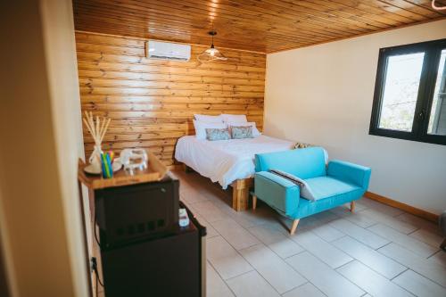 ein Schlafzimmer mit einem Bett und einem blauen Stuhl in der Unterkunft L'Auberge Créole in Saint-Benoît