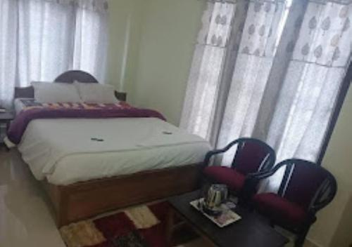 TK Residency Arunachal Pradesh في تاوانج: غرفة نوم صغيرة بسرير وكرسيين