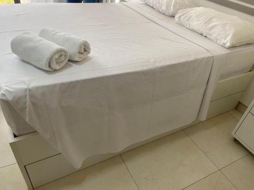 a bed with white sheets and towels on it at MANAÍRA APART HOTEL in João Pessoa