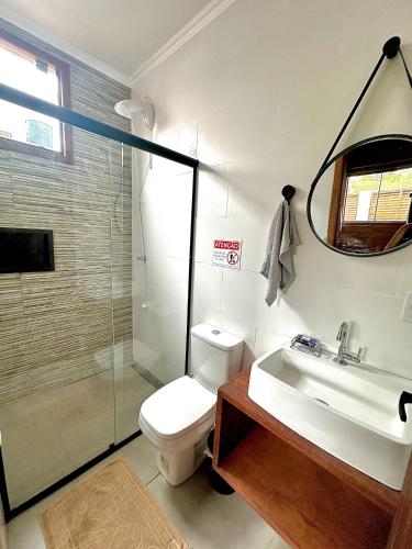 a bathroom with a toilet and a sink and a mirror at POUSADA ROSA e POESIA in Praia do Rosa