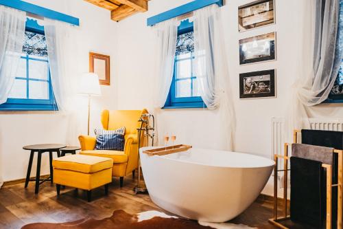 a bathroom with a tub and a chair and a table at Emese Guesthause in Şiclod