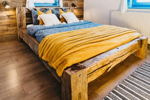 a large wooden bed with a yellow blanket on it at Emese Guesthause in Şiclod