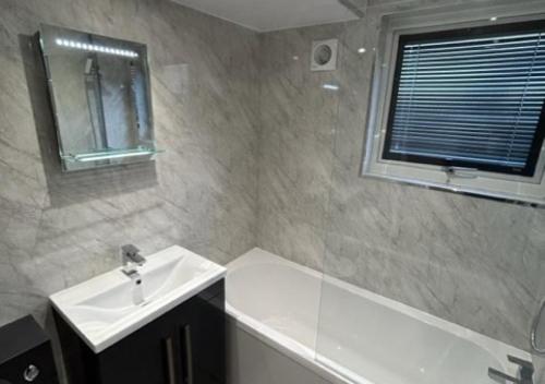 a bathroom with a sink and a bath tub at Pebbles in Abersoch