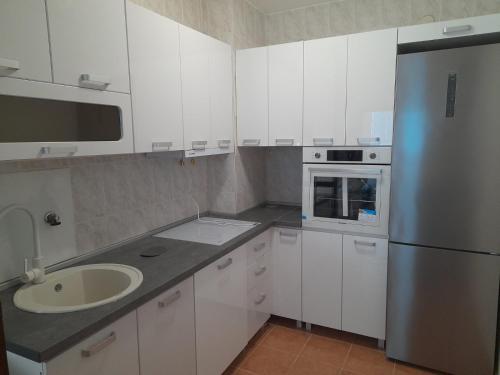 een witte keuken met een wastafel en een koelkast bij Apartment Tijana in Sutomore