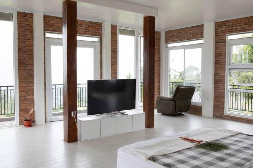 ein Wohnzimmer mit einem Flachbild-TV und Fenstern in der Unterkunft Villa Arum Dalu in Semplak