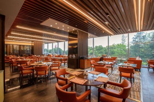 a restaurant with tables and chairs and large windows at Hilton Nanjing Riverside in Nanjing