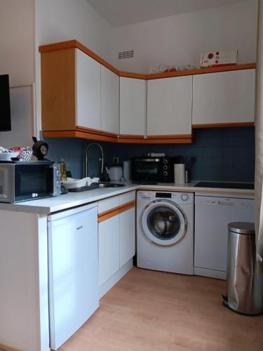 une cuisine avec des armoires blanches et une machine à laver dans l'établissement Le Fayolle - Lumineux 2 pièces en centre-ville, à Dieppe