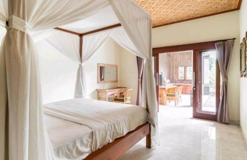 um quarto com uma cama de dossel e uma secretária em Rendira villa 2 em Ubud