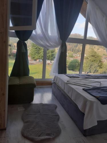a bedroom with a bed and a large window at PENSIUNEA Bori in Gura Humorului