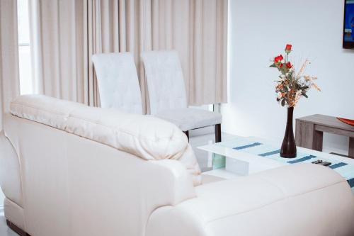 a living room with a white couch and two white chairs at City Apartments at Freedom Plaza in Windhoek