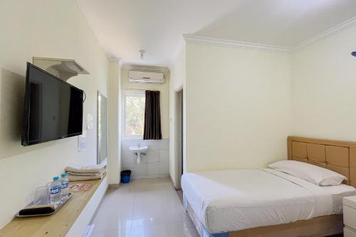 a bedroom with a bed and a flat screen tv at Papa Kana Farm Mitra RedDoorz At Pacet Mojokerto in Mojokerto
