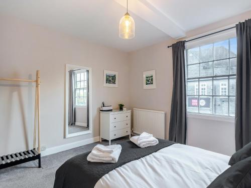 a bedroom with a bed with a dresser and a window at Castle Townhouse in Knaresborough