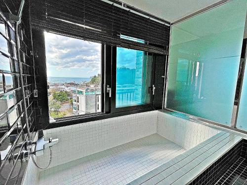 a bathroom with a bath tub with a large window at Nine Boutique Hotel in Seogwipo