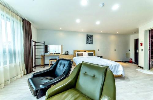 a bedroom with a bed and a couch and a chair at Nine Boutique Hotel in Seogwipo