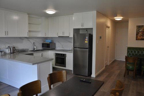 a kitchen with white cabinets and a stainless steel refrigerator at Modern 3-bedroom Katoomba townhouse (nature view) in Katoomba