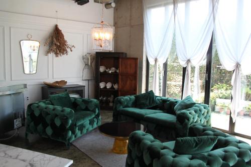 a living room with green furniture and a large window at Nine Boutique Hotel in Seogwipo