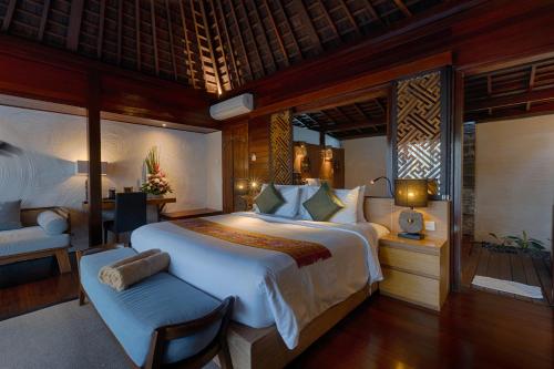 ein großes Schlafzimmer mit einem großen Bett und einem Stuhl in der Unterkunft Black Penny Villas Ubud in Ubud