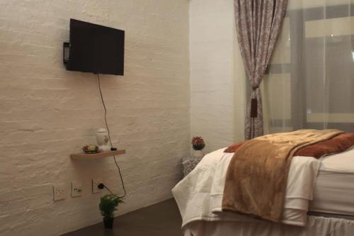 Un dormitorio con una cama y un televisor en la pared. en The Genesis @ Craftsmannship, en Johannesburgo