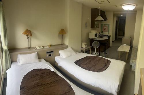 um quarto de hotel com duas camas e uma cozinha em フューデイズコンドミニアム定山渓106号室 em Jozankei