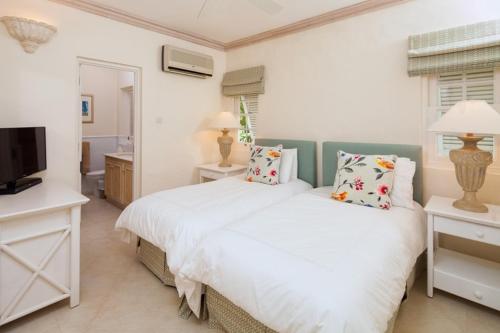 a white bedroom with a bed and a television at Coconut Grove 8 Luxury Villa by Island Villas in Saint James