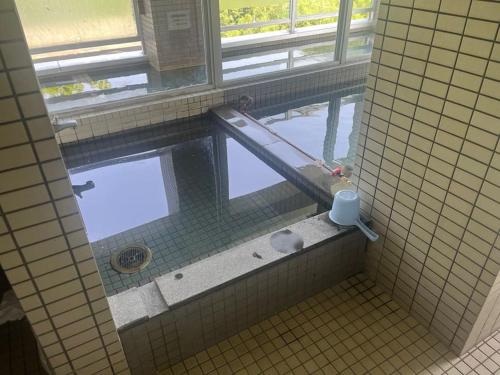 uma casa de banho em azulejo com uma piscina e uma janela em フューデイズコンドミニアム定山渓106号室 em Jozankei