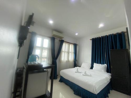 a bedroom with a white bed and blue curtains at SUBINH HOTEL AND RESTAURANT in Pakse
