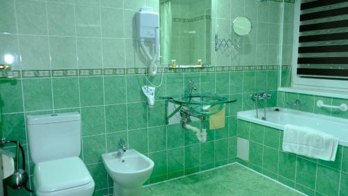 a green tiled bathroom with a toilet and a sink at BUKHARA GRAND HOTEL in Bukhara