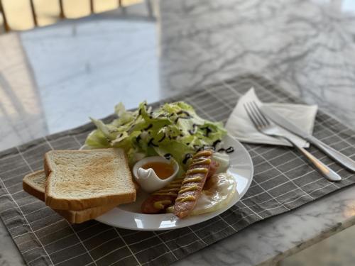 a plate of food with sausage and salad and toast at Nine Boutique Hotel in Seogwipo
