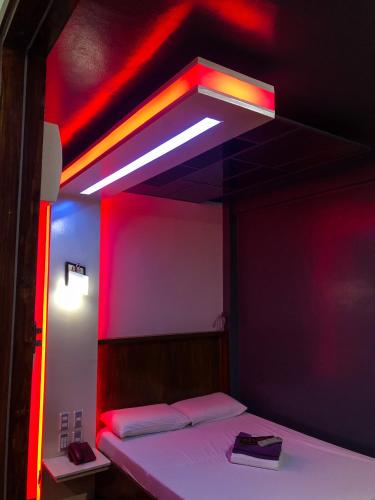a room with a bed with a red light at Harimariz Dormitory Hotel Official in Dumaguete