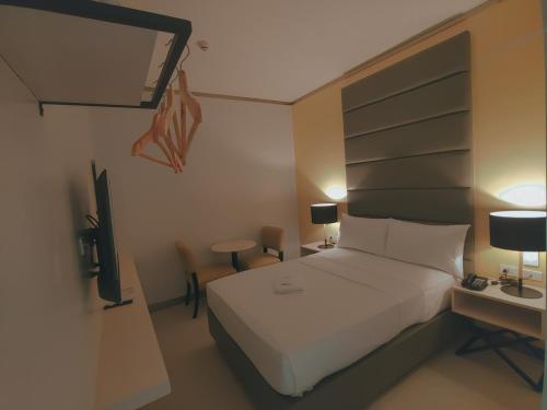 a bedroom with a white bed and a television at Yes Hotel San Ildefonso Bulacan in Buliran