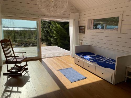 um quarto com uma cama, uma cadeira e um alpendre em Beautiful house in the nature with private river access em Luleå