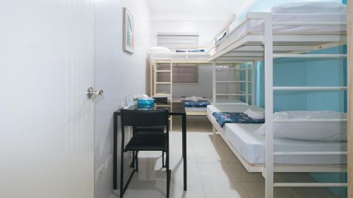 a room with bunk beds with a desk and a bed at Catlea Inn in Manila