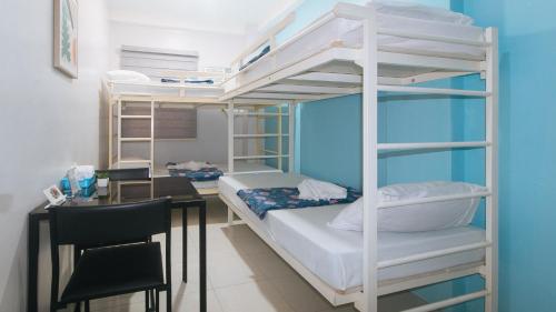 a bedroom with a bunk bed with a desk and a deskablish at Catlea Inn in Manila