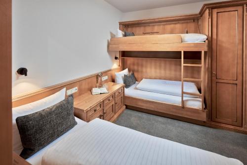 a bedroom with two bunk beds and a desk at Hotel Gletscherblick in Sankt Anton am Arlberg