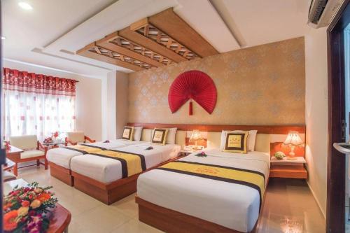 a hotel room with three beds and a red flower on the wall at Boss Place 306-308 Nguyen Thien Thuat Street, District 3 - by Bay Luxury Hotel in Ho Chi Minh City