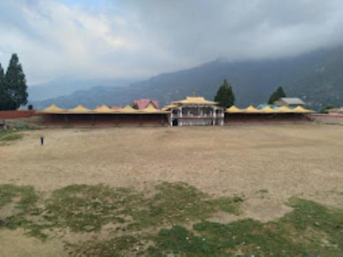 a large building in a field with a mountain at HOTEL GREEN VIEW BOMDILA,Bomdila in Bomdila