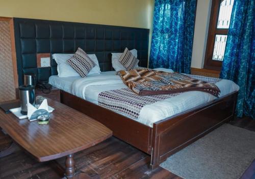 a bedroom with a bed with a table and blue curtains at Himalaya Mount View Resort Uttarakhand in Kausani