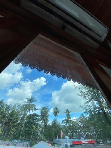 a window in a bus with palm trees in the background at Ruan Mai Naiyang Beach Resort in Nai Yang Beach